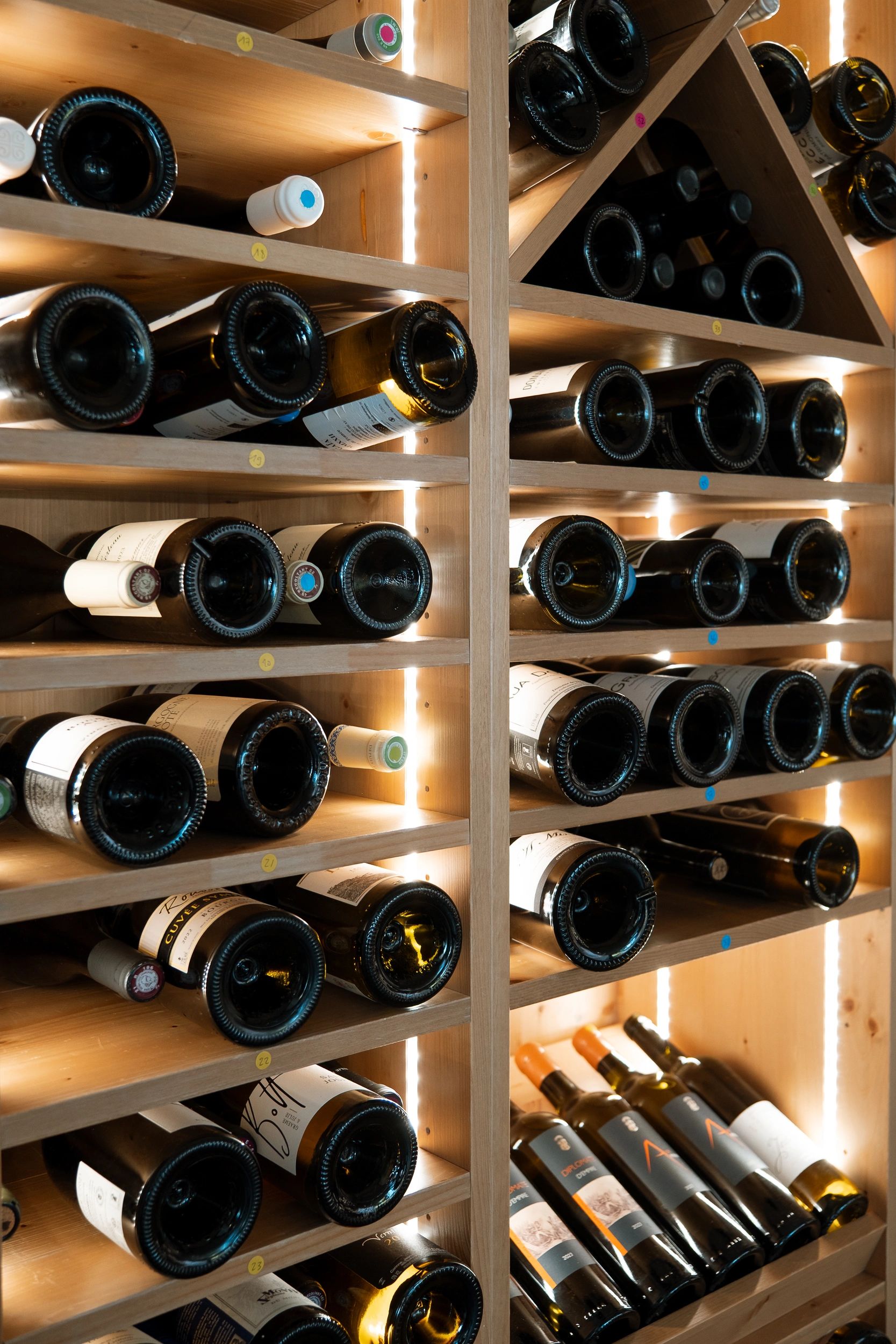 Élégante cave à vin moderne en bois avec éclairage LED intégré présentant des bouteilles de vin rouge et blanc organisées sur
