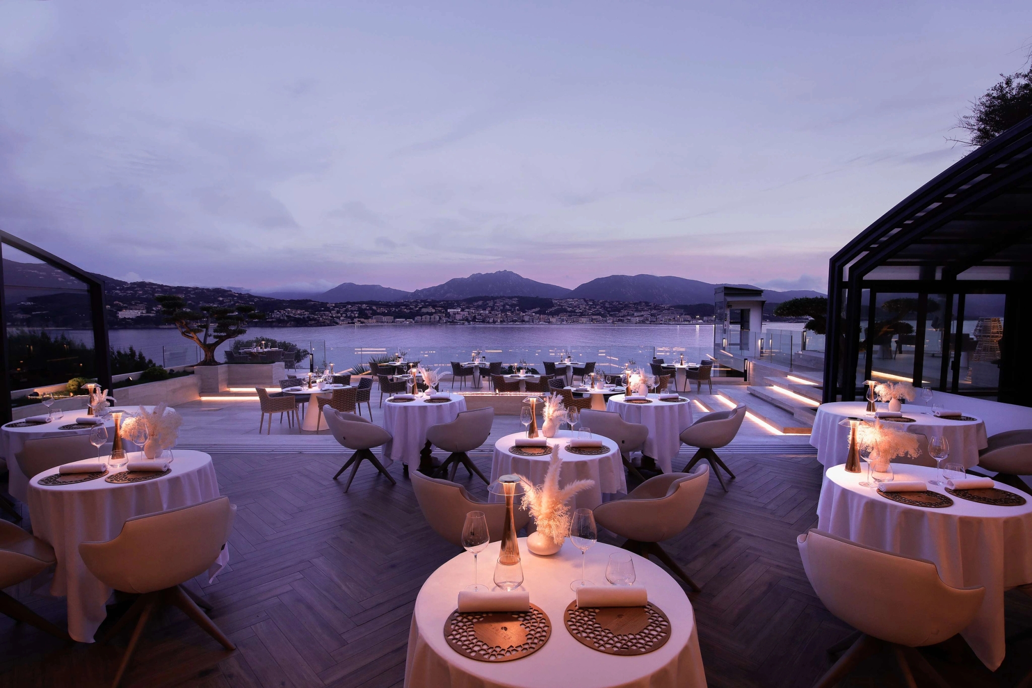 Terrasse de restaurant gastronomique avec vue panoramique sur baie et montagnes au crépuscule